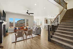 Living area featuring a chandelier, light wood-style floors, ceiling fan, and healthy amount of natural light