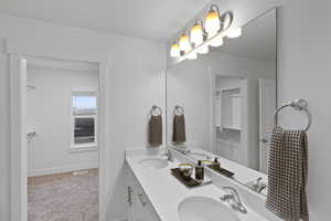 Full bath featuring double vanity and light carpet