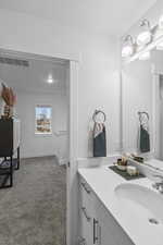 Bathroom with vanity, light colored carpet, and a textured ceiling