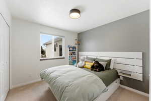 Bedroom with light colored carpet and a closet