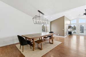 Dining room featuring vaulted ceiling, wood finished floors, healthy amount of natural light, and ceiling fan