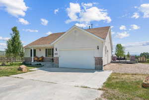 Ranch-style house with a garage, brick siding, concrete driveway, covered porch, and stucco siding