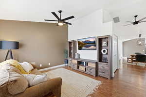 Living room with vaulted ceiling, ceiling fan, wood finished floors, and a chandelier