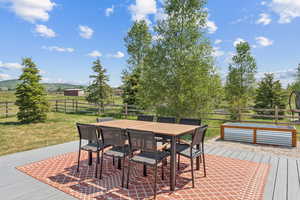 Deck with a fenced backyard, outdoor dining space, and a view of countryside