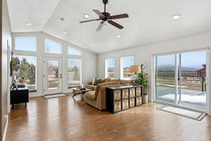 Living room featuring a ceiling fan, plenty of natural light, light wood-style floors, recessed lighting, and a high textured ceiling