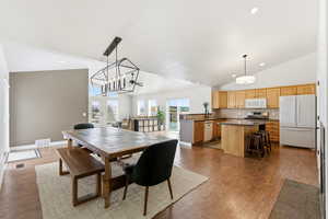 Dining room with french doors, dark wood-style floors, lofted ceiling, and hanging lights