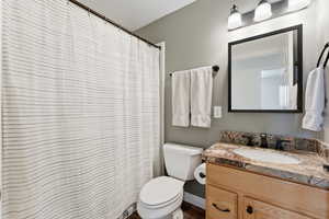 Full bathroom featuring vanity, curtained shower, and dark wood-style floors