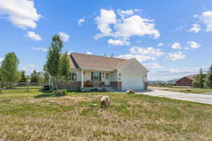 Ranch-style home with an attached garage, driveway, covered porch, and brick siding
