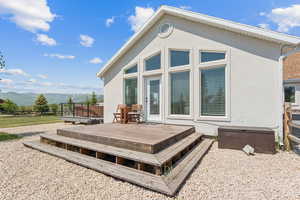 Rear view of property featuring stucco siding and a deck with mountain view