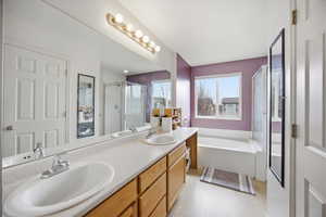 Full bath with double vanity, a stall shower, and a bath