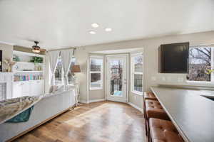 Living room with light wood finished floors, ceiling fan, and plenty of natural light