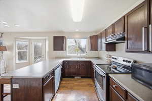 Kitchen with a peninsula, stainless steel appliances, dark wood finish cabinetry, and recessed lighting