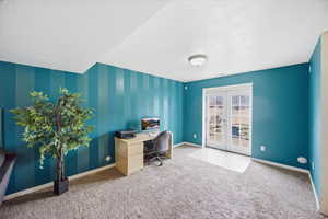 Office area with french doors, a textured ceiling, light colored carpet, and an accent wall
