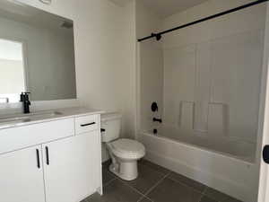 Bathroom with vanity, dark tile patterned flooring, and shower / washtub combination