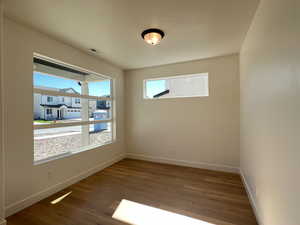 Spare room featuring dark wood-type flooring and baseboards
