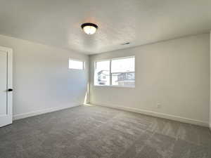Empty room featuring dark colored carpet and baseboards
