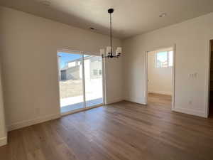 Unfurnished dining area with hanging lights, dark wood-type flooring, and healthy amount of natural light