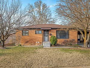 Ranch-style home with brick siding, a front yard, and a shingled roof