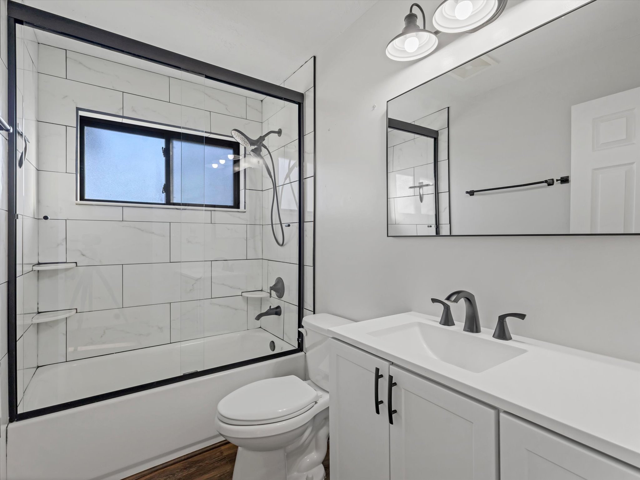 Bathroom featuring vanity, combined bath / shower with glass door, and dark wood-type flooring