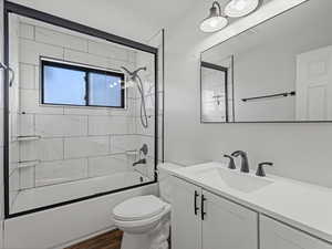 Bathroom featuring vanity, combined bath / shower with glass door, and dark wood-type flooring