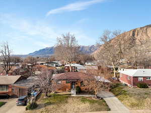 View of front of home with a residential view, a mountain view, and a front yard