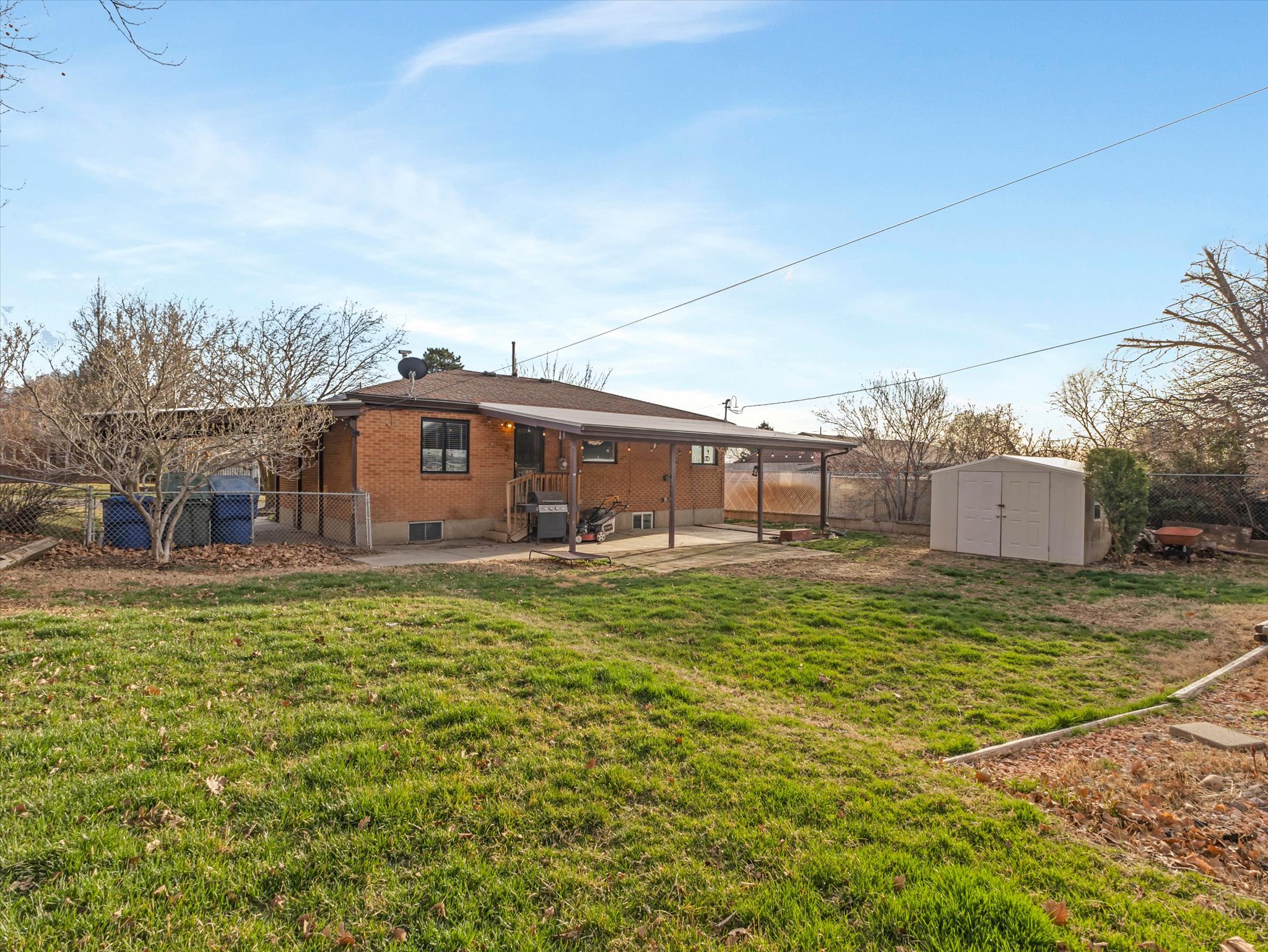 Back of property featuring a fenced backyard, brick siding, a patio, and a storage unit