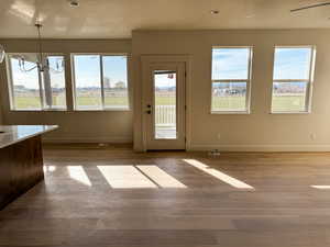 Unfurnished dining area with light wood-style flooring, suspended lighting, plenty of natural light, a textured ceiling, and a ceiling fan