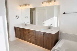 Full bathroom with double vanity, a bath, and light tile patterned floors