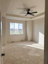 Unfurnished room with a ceiling fan and a tray ceiling
