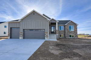 Craftsman-style home featuring board and batten siding, stone siding, an attached garage, and concrete driveway