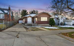 View of front facade with an outdoor structure, brick siding, a detached garage, and a chimney
