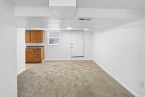 Finished below grade area with light carpet and a textured ceiling