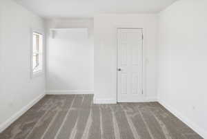 Empty room with dark carpet and baseboards