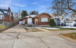 View of front facade with brick siding, an outbuilding, a detached garage, and a chimney