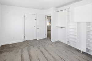 Unfurnished bedroom featuring light carpet and baseboards