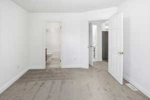 Unfurnished bedroom featuring light carpet and ensuite bath