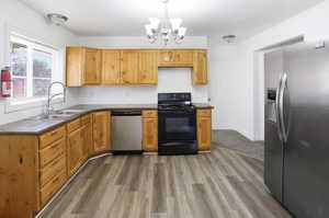 Kitchen featuring stainless steel appliances, suspended lighting, and dark wood-style floors