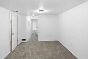 Unfurnished room featuring a textured ceiling and carpet