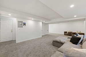Carpeted living area featuring recessed lighting and electric panel