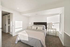Bedroom featuring a barn door, carpet flooring, connected bathroom, and recessed lighting