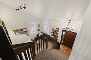 Staircase featuring hanging lights, carpet floors, and a textured ceiling
