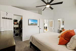 Bedroom with a walk in closet, dark carpet, lofted ceiling, and ceiling fan