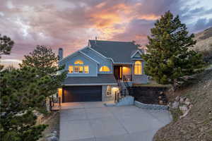 View of front of home with a garage, concrete driveway, a shingled roof, and a chimney