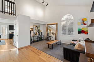 Living area featuring light wood-type flooring, a high ceiling, and track lighting