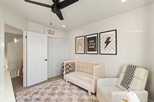 Carpeted bedroom with a closet, ceiling fan, a crib, and recessed lighting