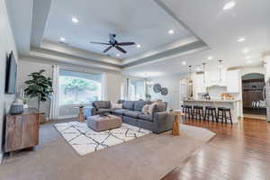 Living room with arched walkways, a ceiling fan, recessed lighting, and dark wood-style flooring