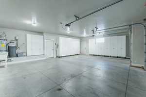 Garage featuring strapped water heater and baseboards