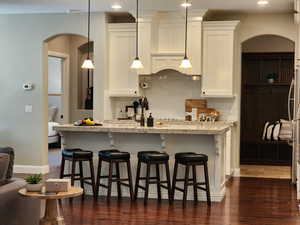 Kitchen featuring arched walkways, a breakfast bar area, and white cabinets