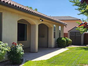 View of exterior entry featuring a yard, a tile roof, and stucco siding