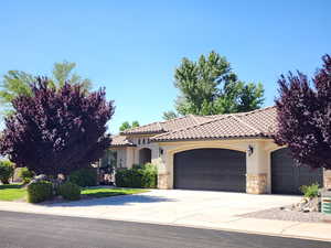 Mediterranean / spanish home featuring stone siding, a garage, driveway, stucco siding, and a tiled roof